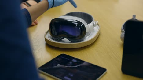 Una-Persona-Que-Lleva-Guantes-De-Látex-Azules-Muestra-Los-Auriculares-Apple-Vision-Pro-VR-Al-Cliente