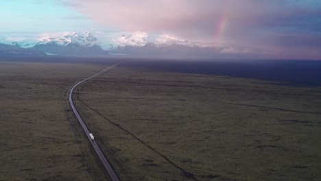 Aerial-shot-of-a-truck-driving-through-the-Ring-Road-in-Iceland-with-the-Vatnajokull-glacier-and-mountains-in-the-background