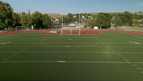 Drone-flying-over-football-goals-at-a-empty-sport-field-in-sunny-Santa-Clarita,-CA,-USA