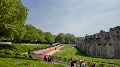 A-vibrant-daytime-scene-at-the-Tower-of-London,-England,-as-travelers-and-visitors-leisurely-stroll-in-front-of-this-iconic-historical-site,-concept-of-living-history-and-cultural-exploration