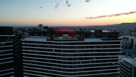 Aerial-shot-of-Brisbane,-Emporium-Hotel,-camera-slowly-flying-away-from-buildings-rooftop-pool-and-bar