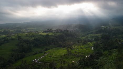Sun-rays-breaking-through-moody-clouds-lighting-Jatiluwih-Rice-Terraces-in-the-volcanic-hills-of-central-Bali,-Indonesia