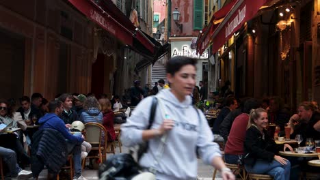 People-enjoy-dining-at-busy-outdoor-cafe-on-narrow-street-of-Old-Town-Nice