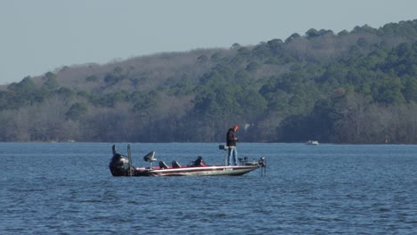 Man-standing-in-a-fishing-boat-on-a-lake-during-winter