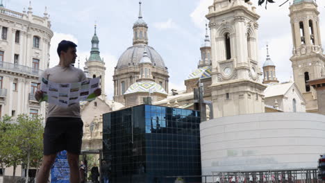 Tourist-Reading-A-Map-On-The-Streets-Of-Zaragoza,-Spain,-El-Pilar-in-the-background