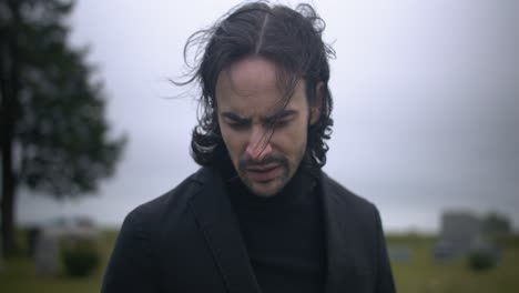 Young-man-in-black-suit-pays-respects-to-the-dead-in-cemetery