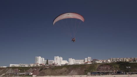 Vista-Aérea-De-Un-Parapente-Motorizado-Volando-Sobre-La-Playa-De-Arena-En-Un-Día-Soleado,-Portugal