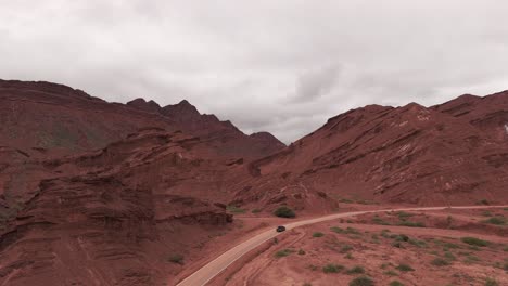 Car-on-winding-road-through-stunning-red-rock-canyon-landscape-in-Route-68,-Quebrada-de-las-Conchas,-Argentina