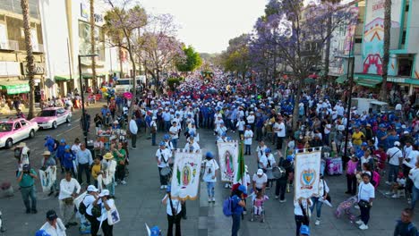 Fly-over-dolly-in-mexican-flag,-virgin-banners-and-massive-pilgrimage-to-the-basilica-of-Guadalupe-on-a-sunny-day,-CDMX,-Mexico