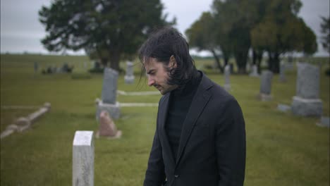 Sad,-emotional-man-wearing-black-suit-grieving-in-graveyard