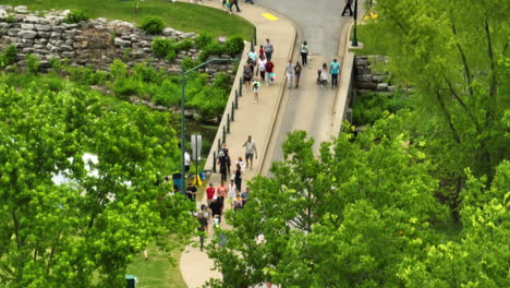 People-On-Footbridge-Across-Sager-Creek-During-50th-Dogwood-Festival-In-Siloam-Springs,-Arkansas