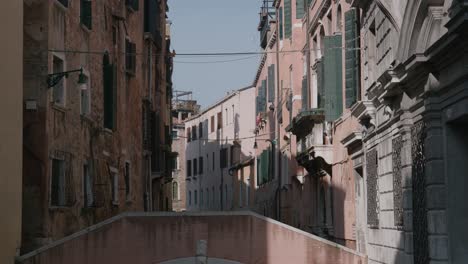 Historic-narrow-street-with-weathered-buildings-and-green-shutters-in-Venice,-Italy