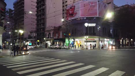 Sonnenuntergang-Skyline-Verkehr-In-Buenos-Aires-Stadtviertel-Menschen-Geschäfte-Kommerzielle-Aktivität-In-Der-Nacht-In-Argentinischen-Flores-Nachbarschaft,-Autos-Busse-Taxis-Fahren,-Hohe-Gebäude-Bereich