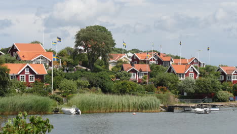 Summer-Cabins-and-Swedish-Flags-at-Brandaholm,-Karlskrona,-Sweden,-Pan-shot