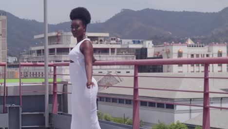 Una-Joven-Negra-Con-Un-Vestido-Blanco-En-Una-Azotea,-Mirando-La-Ciudad