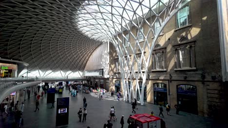 Overlooking-People-walking-along-concourse-at-London-King's-Cross-railway-station,-showcasing-the-concept-of-urban-transit-and-bustling-travel-hubs