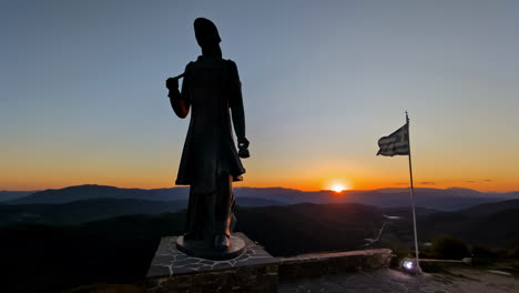 Das-Griechische-Denkmal-Zu-Ehren-Der-Tapferen-Frauen-Von-Pindos-Bei-Sonnenuntergang-Mit-Einer-Griechischen-Flagge