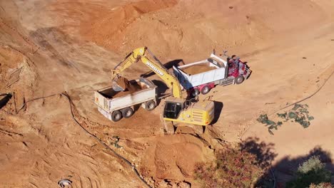 Tracked-excavator-loading-dirt-into-the-rear-bin-of-a-truck-and-trailer