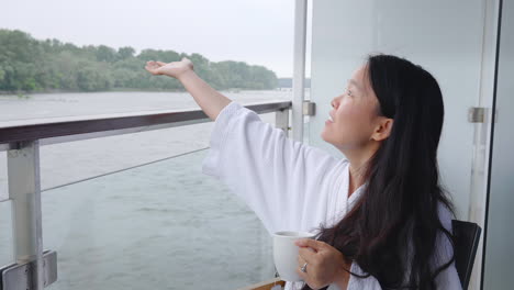 Chinese-girl-in-bathrobe-checking-if-it-rains-from-cruise-room-balcony