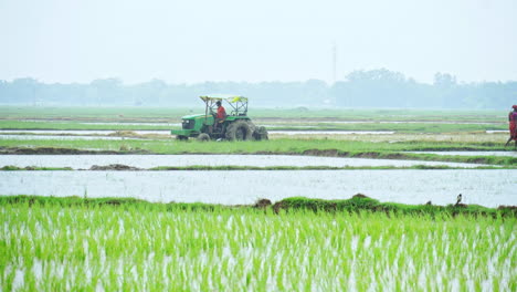 In-the-monsoon-season,-a-tractor-is-plowing-a-cultivated-land-for-soil-preparation-before-seeding