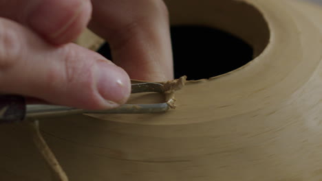 Handheld-close-up-shot-of-removing-clay-from-a-vase-during-pottery-process