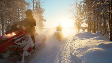Group-of-snowmobiles-emerge-from-back-lit-sunrise-glow-in-Lapland-snowy-forest-wilderness