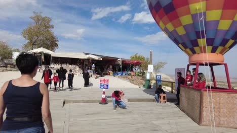 A-woman-walking-from-behind-towards-a-Hot-Air-balloon-attraction-Stand-in-Cappadocia