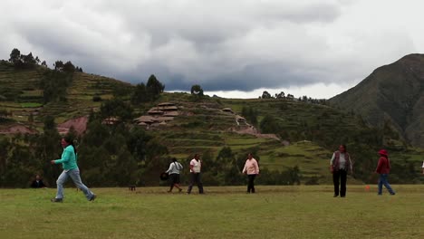 Andean-local-women-playing-female-football-in-Chinchero,-Cusco,-Perú-with-tourist