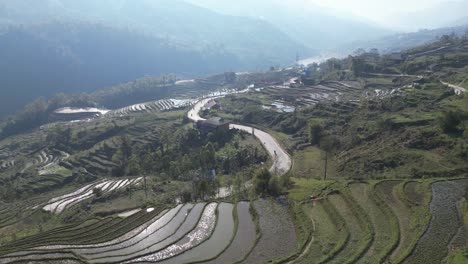 Aerial-drone-shot-of-sunlight-reflecting-in-bright-green-rice-terraces-in-the-mountains-of-Sapa,-Vietnam