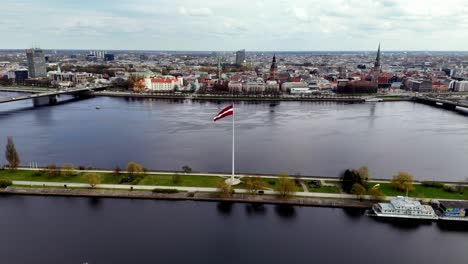 Eine-Riesige-Flagge-Weht-An-Einem-Riesigen-Fahnenmast-In-Riga,-Lettland,-Europa-–-Seitliche-Aufnahme