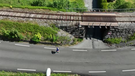 Runner-jogging-at-Tunesvegen-in-Garnes-arna,-birdseye-aerial-following-sideways-from-above