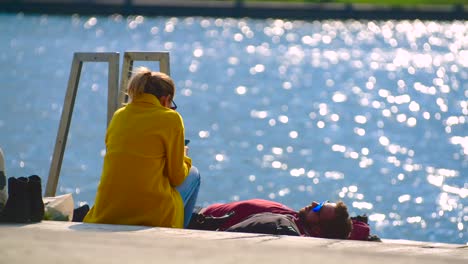 Feliz-Pareja-Joven-Tomando-El-Sol-En-La-Orilla-Del-Río-Danubio-En-Un-Día-Soleado,-Viena