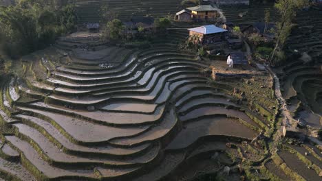 Aerial-drone-shot-of-villages-amidst-bright-green-rice-terraces-in-the-mountains-of-Sapa,-Vietnam