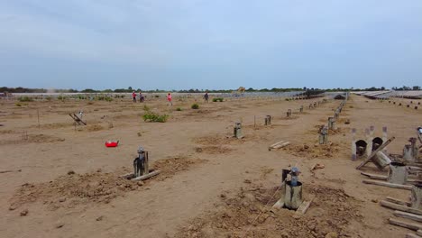 Weite-Schwenkansicht-Verschiedener-Bauarbeiter-Und-Ingenieure,-Die-Betonpfahlrahmenformen-Aufstellen-Und-Vermessungen-Auf-Der-Baustelle-Eines-Solarparks-In-Gambia,-Westafrika-Durchführen