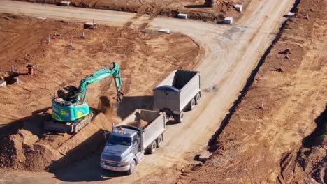 Low-aerial-view-of-excavator-loading-a-truck-and-trailer-with-dirt