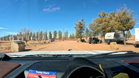 POV---Driving-through-RV-Park-with-RVs,-trailers,-and-tall-cedar-trees