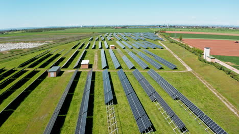 A-vast-solar-farm-with-rows-of-solar-panels-under-a-clear-blue-sky,-aerial-view