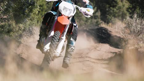 Motorcycle-rider-in-slow-motion-toward-camera,-foreground-bushes