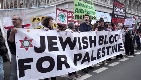 Menschen-Halten-Ein-Großes-Weißes-Banner-Mit-Der-Aufschrift-„Jüdischer-Block-Für-Palästina“-Hoch,-Auf-Einem-Anderen-Steht-„Israelischen-Botschafter-Wegen-Anstiftung-Zum-Völkermord-Ausweisen“-Zu-Beginn-Einer-Protestkundgebung-Am-Nakba-Tag.