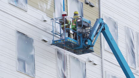 Commercial-painters-spray-the-siding-of-new-construction