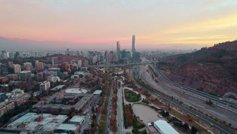 Toma-Panorámica-De-Drones-Del-Horizonte-De-Santiago-Desde-El-Parque-Bicentenario,-Puesta-De-Sol-En-Chile