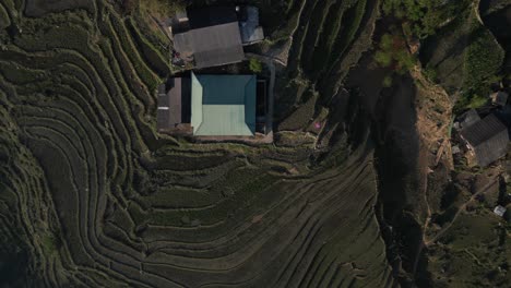 Aerial-drone-shot-of-villages-amidst-bright-green-rice-terraces-in-the-mountains-of-Sapa,-Vietnam