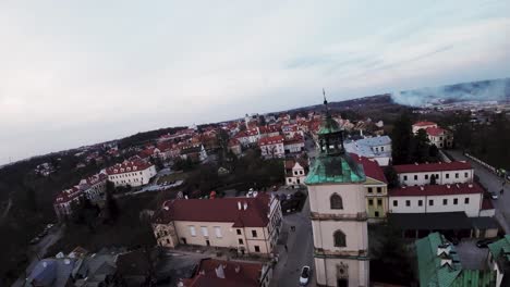 Toma-De-Drones-Fpv-Del-Casco-Antiguo-De-Sandomierz,-Polonia,-Volando-Junto-A-La-Torre-De-Una-Iglesia,-Por-La-Noche