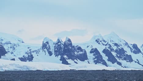 Montañas-Invernales-Al-Atardecer-En-La-Antártida-Y-Océano-Con-Nubes-Y-Cielo-Dramáticos,-Paisajes-Asombrosos-En-La-Costa-De-La-Península-Antártica,-Paisajes-Costeros-Al-Atardecer-En-Una-Escena-Helada-Y-Nevada-En-Clima-Frío