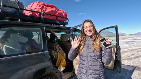 Hermosa-Mujer-Rubia-Aventurera-Saluda-Sonriendo-Mientras-Entra-Al-Auto