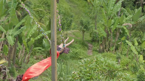 A-woman-joyfully-swings-amidst-the-lush-rice-terraces-of-Tegallalang,-Bali,-Indonesia