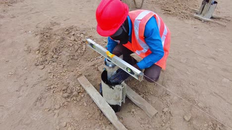 Black-construction-worker-installs-and-levels-concrete-pile-frame-mould-and-support-for-solar-PV-concrete-pile-at-Jambur-Solar-power-plant,-Gambia