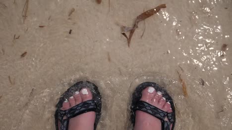 Wave-washes-over-feet-in-sand-on-a-beach-in-Cancun-Mexico