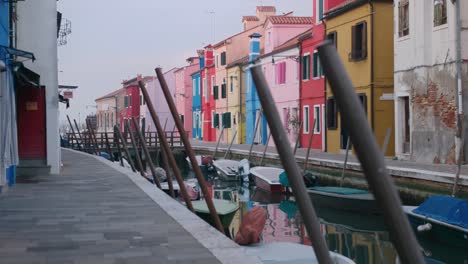 Vibrant,-colorful-houses-along-a-canal-in-Burano-Island,-Venice,-reflecting-on-the-water