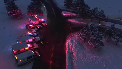 Aerial-orbit-around-ambulances-with-flashing-lights-at-snowy-intersection-in-winter